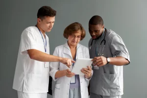 Three doctors collaboratively examining a tablet computer, discussing patient information or medical data