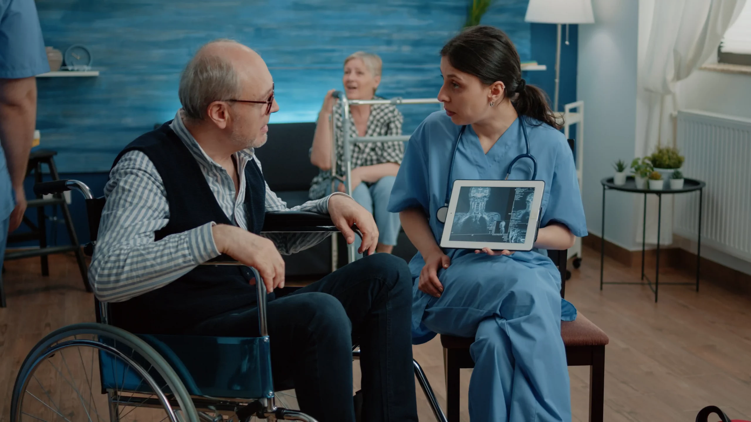 A man in a wheelchair converses with a nurse in a healthcare setting, both engaged in a supportive discussion.