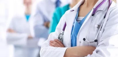 Services A group of healthcare professionals stands confidently; a female doctor in front with folded arms, stethoscope visible, conveying teamwork and professionalism.